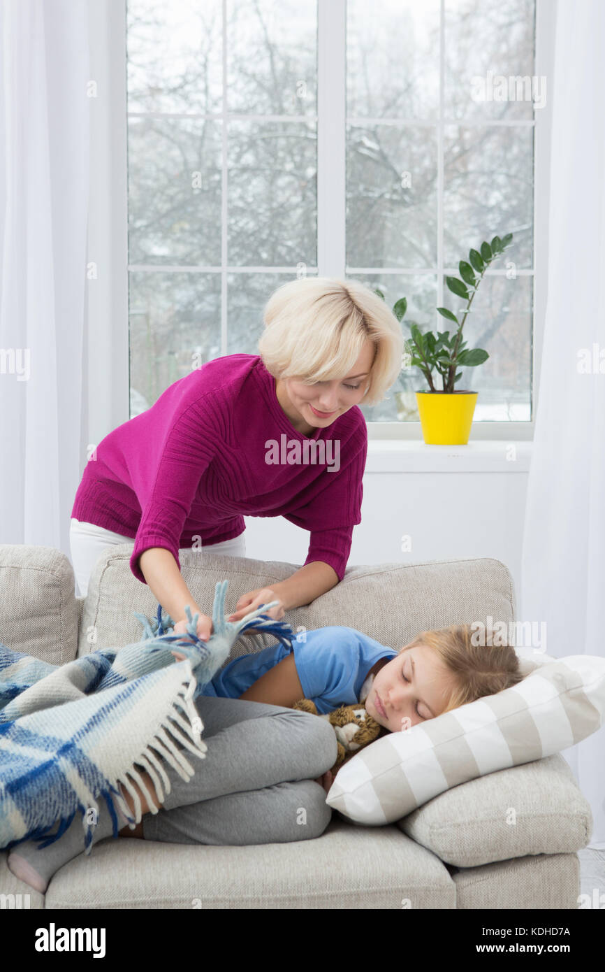 Mother taking care of her sick kid at home. Stock Photo
