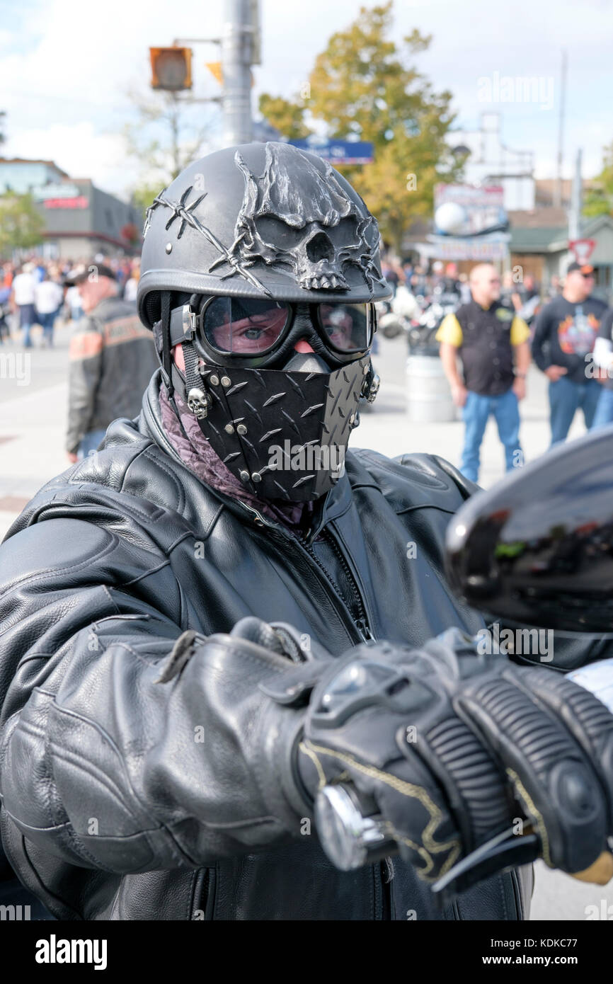 Port Dover, Ontario, Canada, 13th October 2017. Thousands of motorcyclists from all over Canada and the USA get together for The Friday 13th Motorcycle Rally, held every Friday the 13th in Port Dover, Ontario, Canada, since 1981. The event is one of the largest single-day motorcycle events in the world. This year, the mild weather contributed for a large number of bikers and onlookers, with hundreds of custom motorcycles, vendors, live music and interesting people to watch. Male motorcycle rider wearing black outfit, skull helmet and face mask. Credit: Rubens Alarcon/Alamy Live News Stock Photo