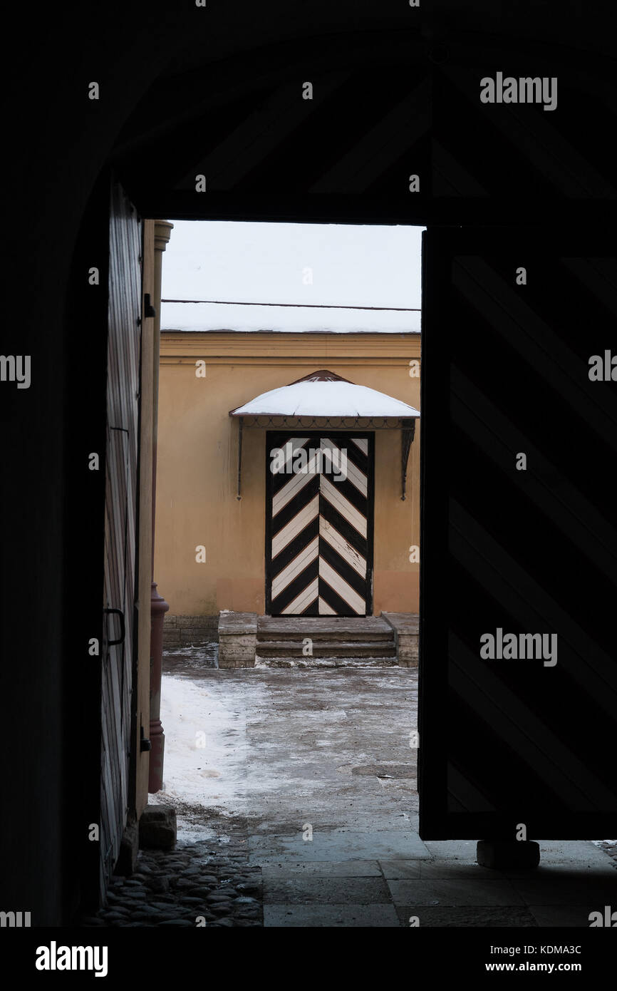 Striped prison door visible from the dark gate in the historical architecture landmark: Peter and Paul fortress in Saint Petersburg, Russia Stock Photo