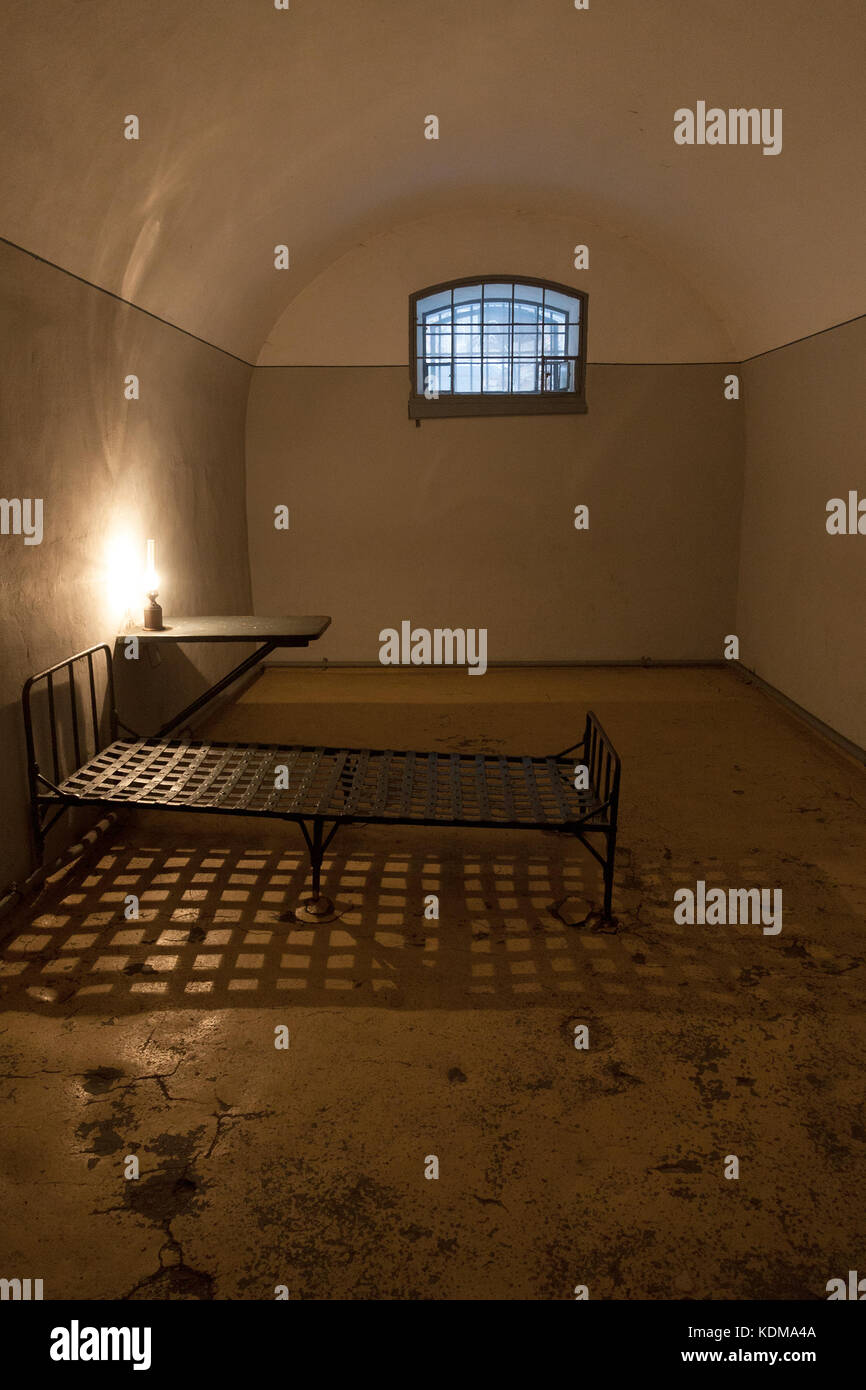 Old jail cell interior in the prison of Peter and Paul fortress in Saint Petersburg, Russia, with a little window, vintage lamp and iron bed. Stock Photo