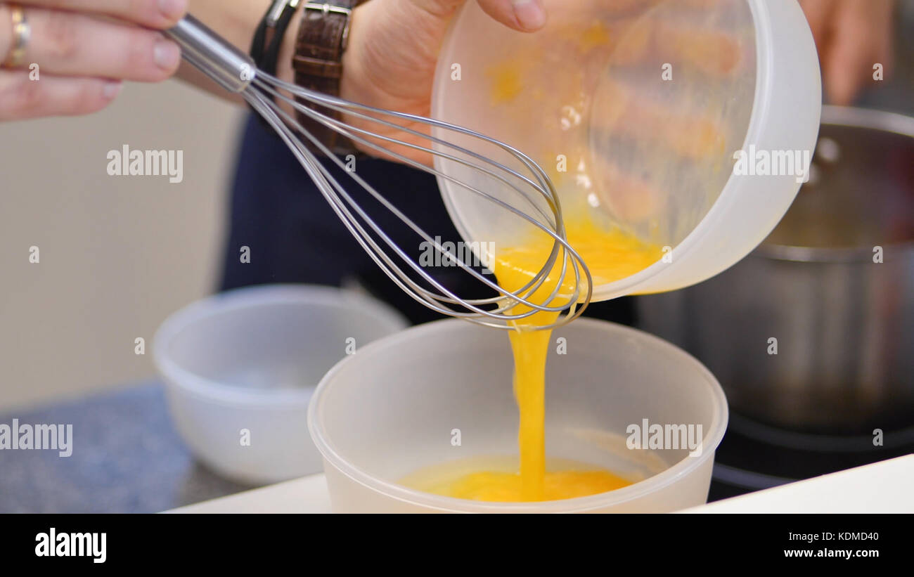 whipped egg yolks with sugar in a glass bowl. Beaten egg yolks in a bowl with whisk. Beaten egg