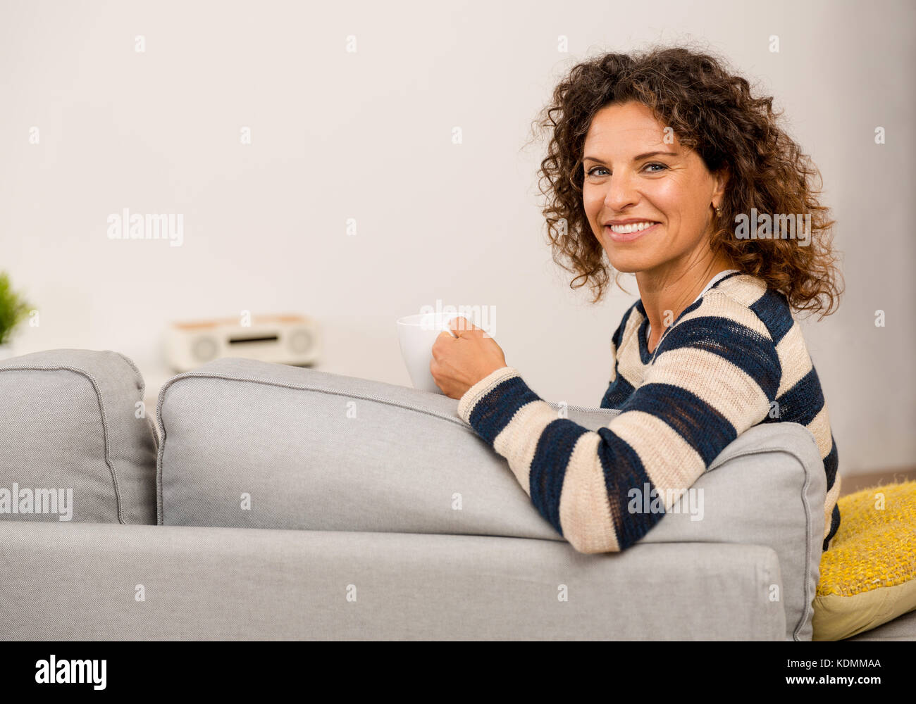 Beautiful woman sitting on the sofa and drinking a coffee Stock Photo ...