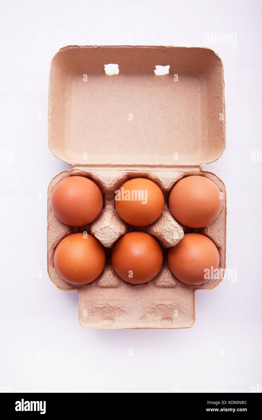 Chicken eggs in egg box on white wooden background Stock Photo - Alamy