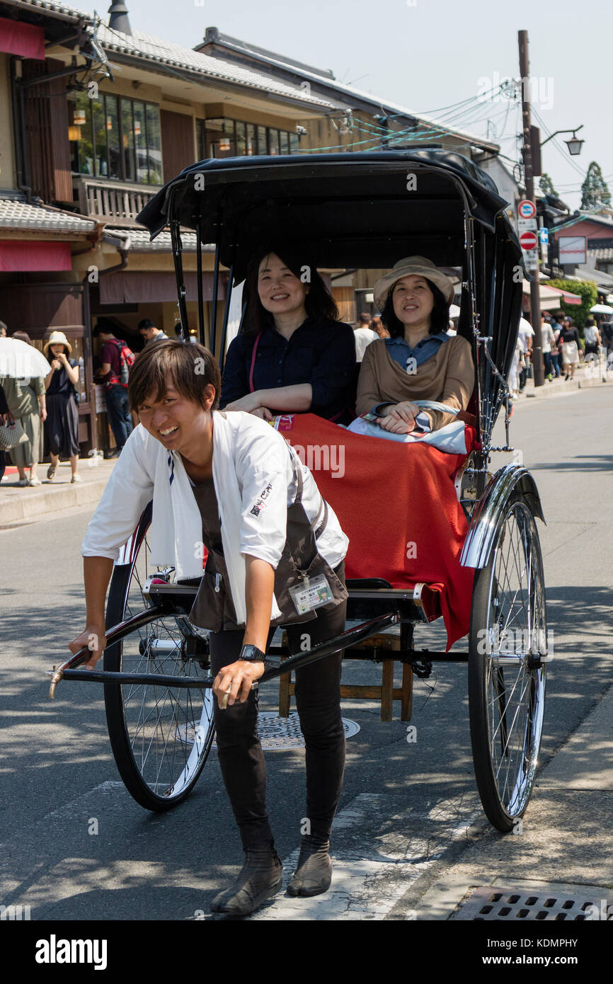 Kyoto, Japan -  May 20, 2017: Traditional human power rickshaw carrying women through the city Stock Photo