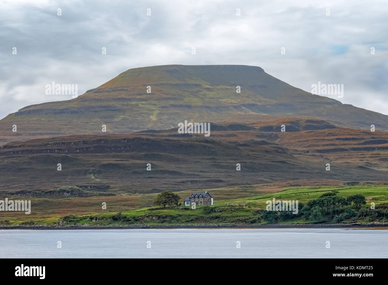 a cottage an the banks of a river, in the shadow of a bleak hill Stock Photo