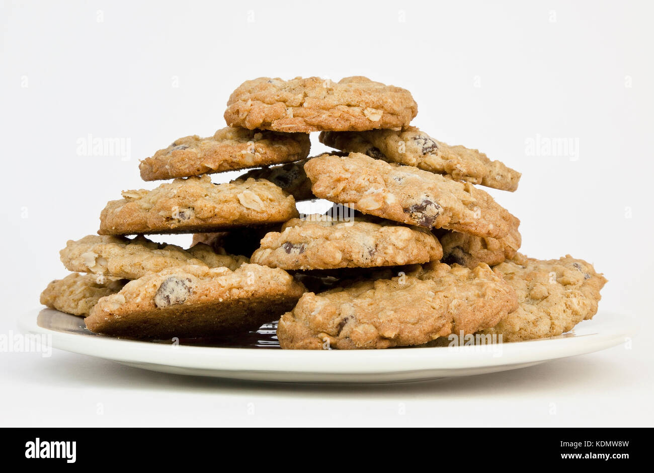 Front view of a plate piled high with homemade oatmeal raisin chocolate chip biscuits cookies on a white background. Stock Photo