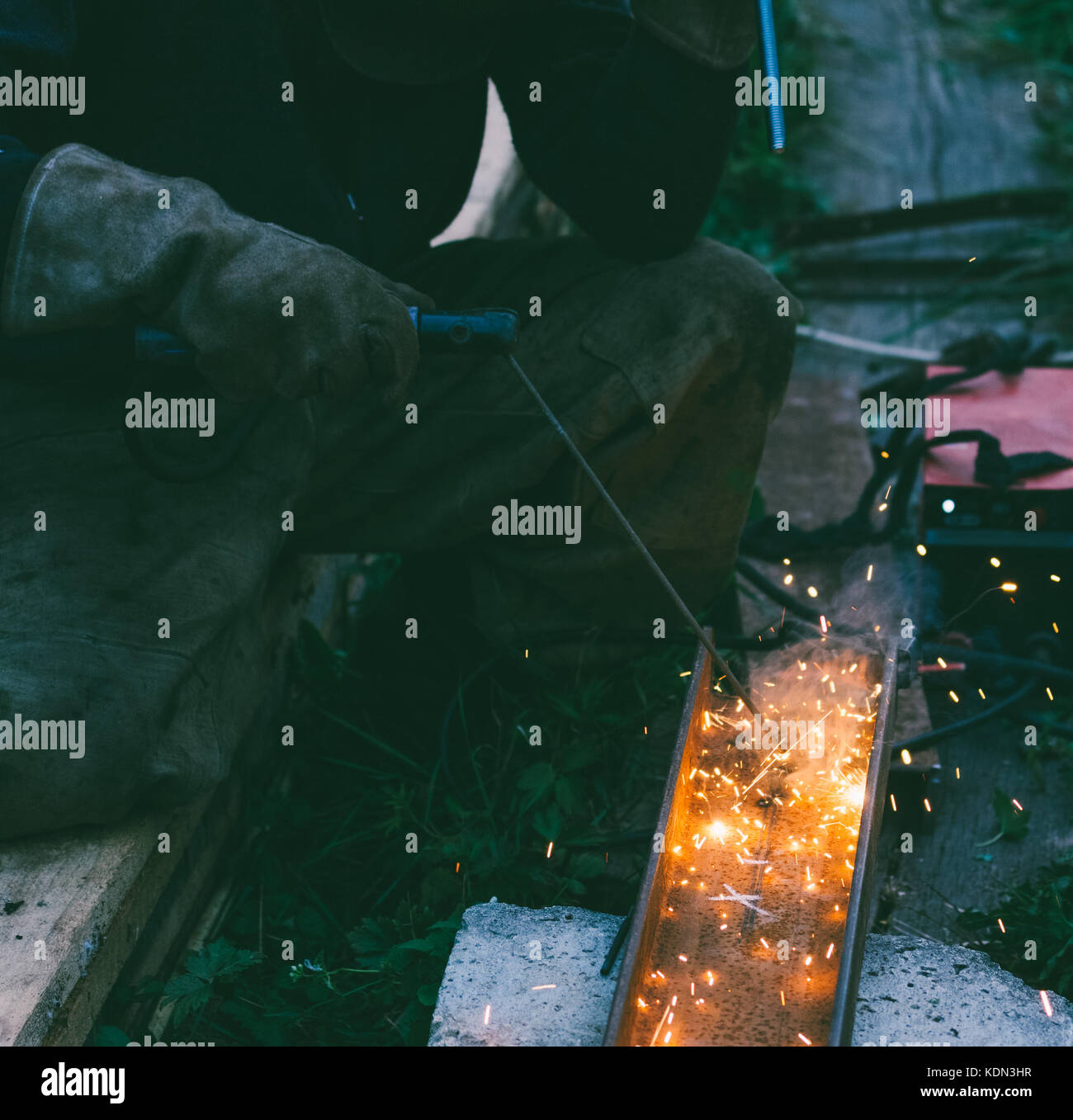 working male welder burns electrode hole in steel channel in the