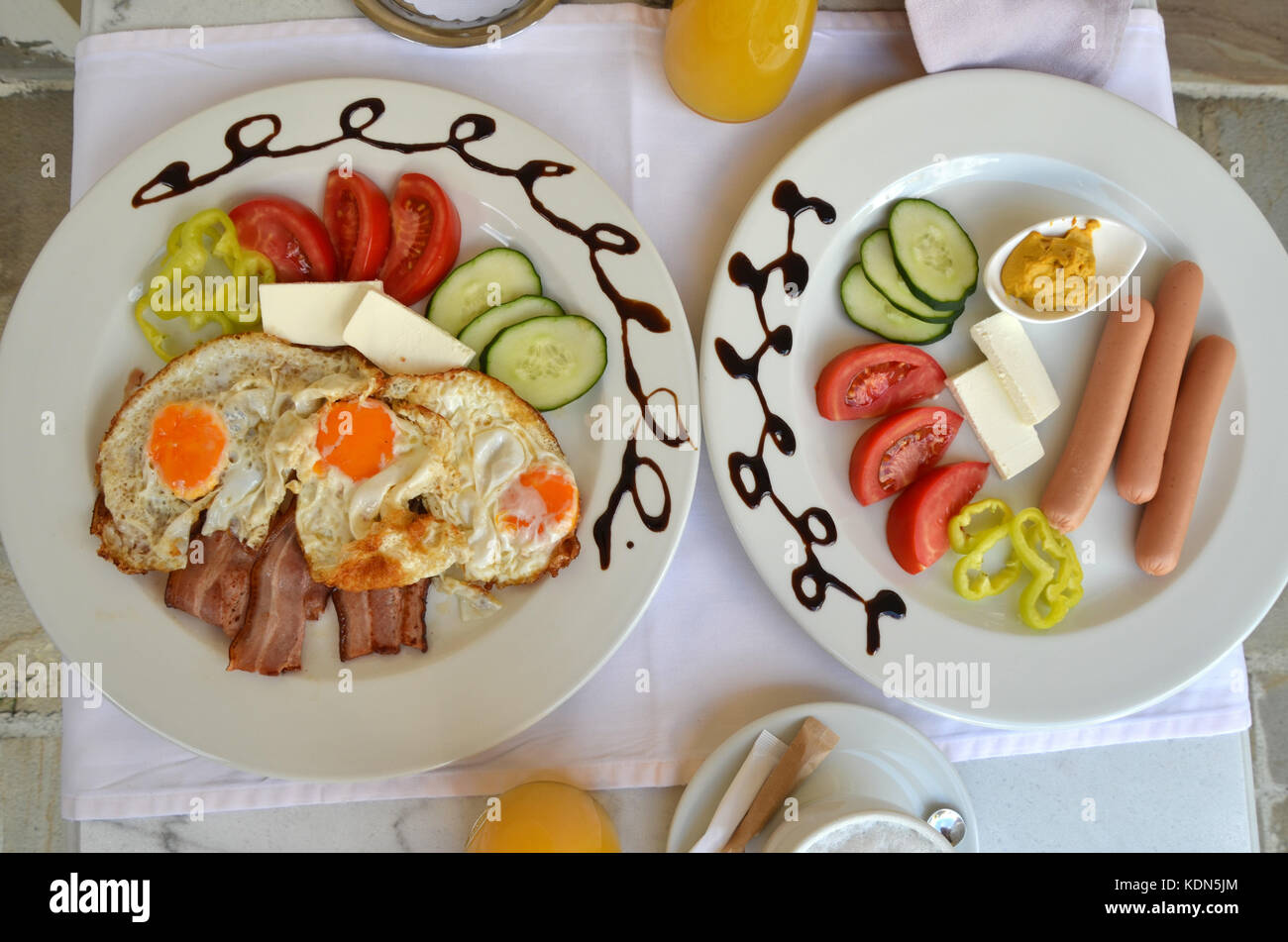Plates with served breakfast - fried eggs, bacon, hot  eggs and fresh vegetables Stock Photo