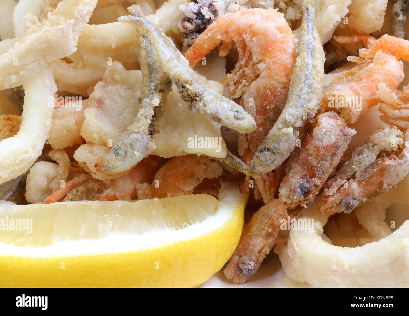 appetizing background of many fried fish with shrimp in a pan in the street food stand and a lemon slices of lemon Stock Photo