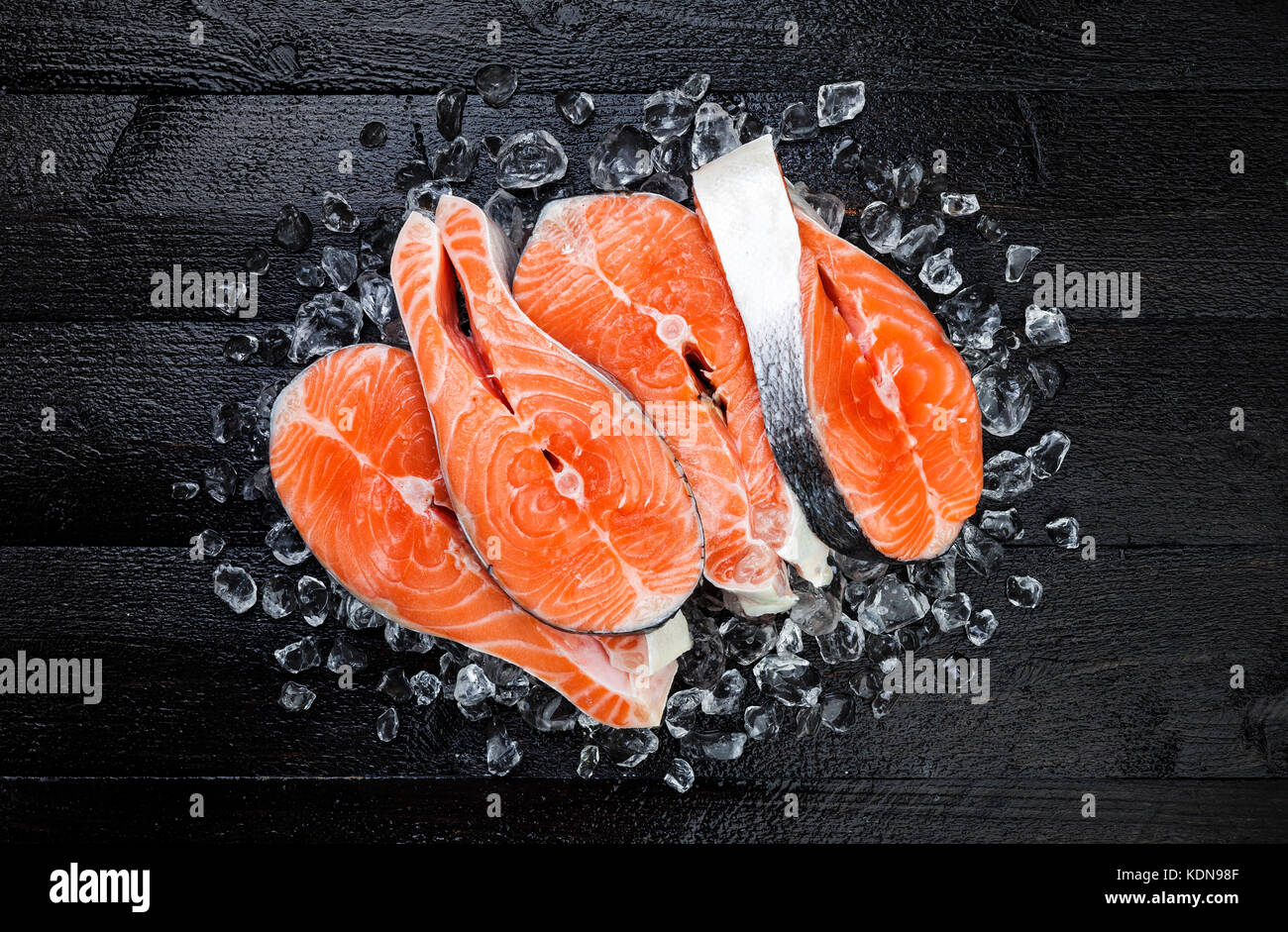Salmon steaks on ice on black wooden table top view Stock Photo - Alamy