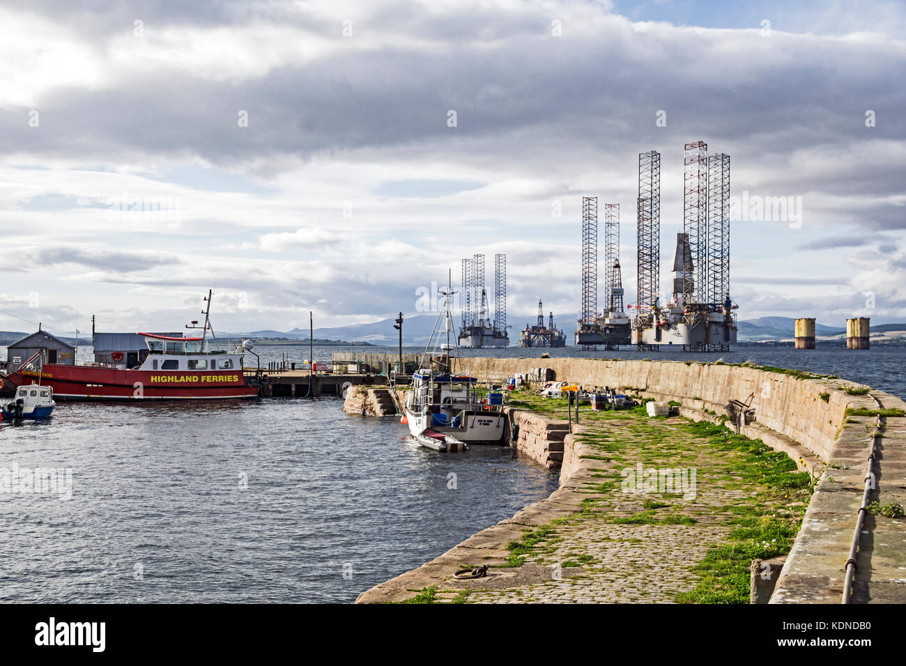 Cromarty harbour with Nigg ferry Renfrew Rose and moored oil platforms in Cromarty Firth at Cromarty Black Isle Scotland UK Stock Photo