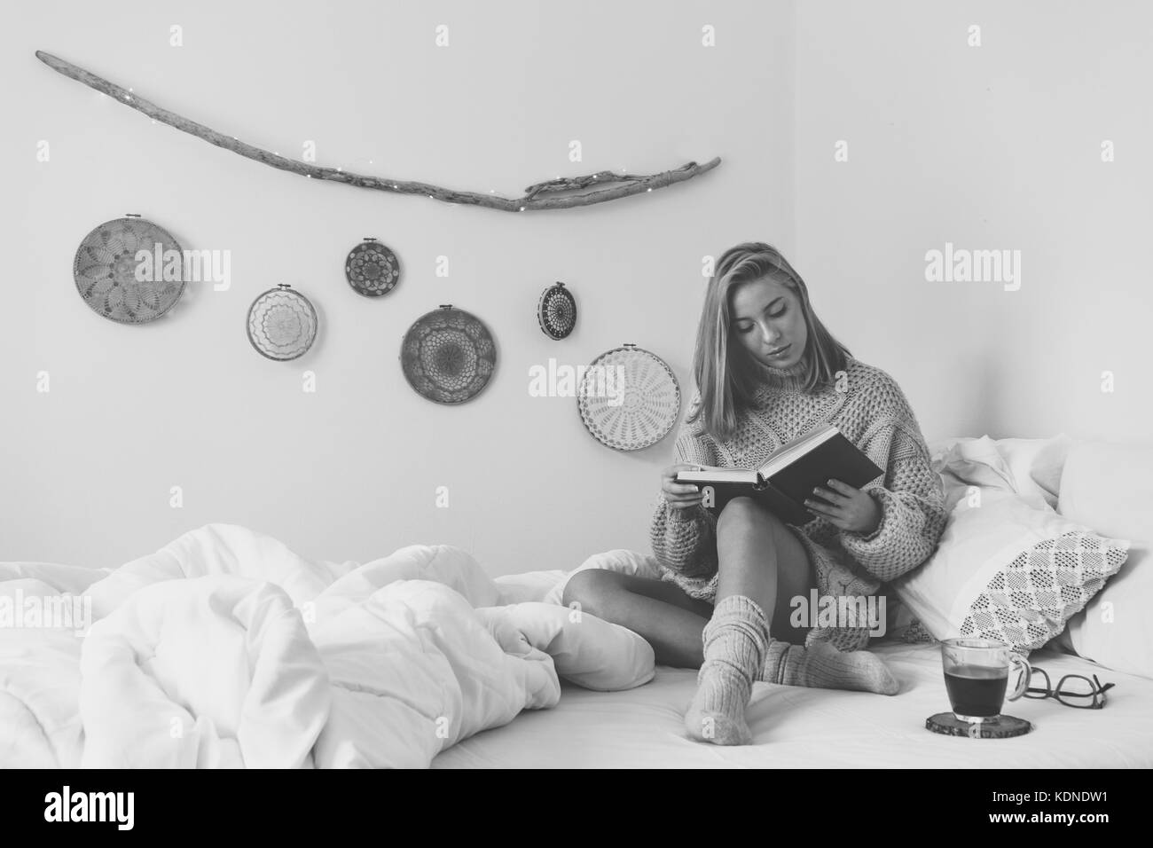 Young woman sitting in bed while reading a book Stock Photo