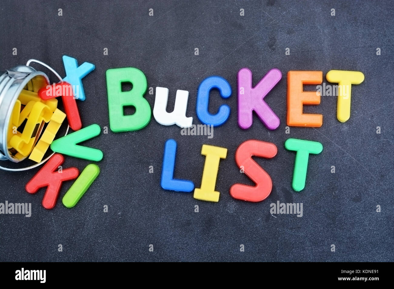 Bucket list concept, things to do in life with iron bucket and magnetic letters on chalkboard Stock Photo