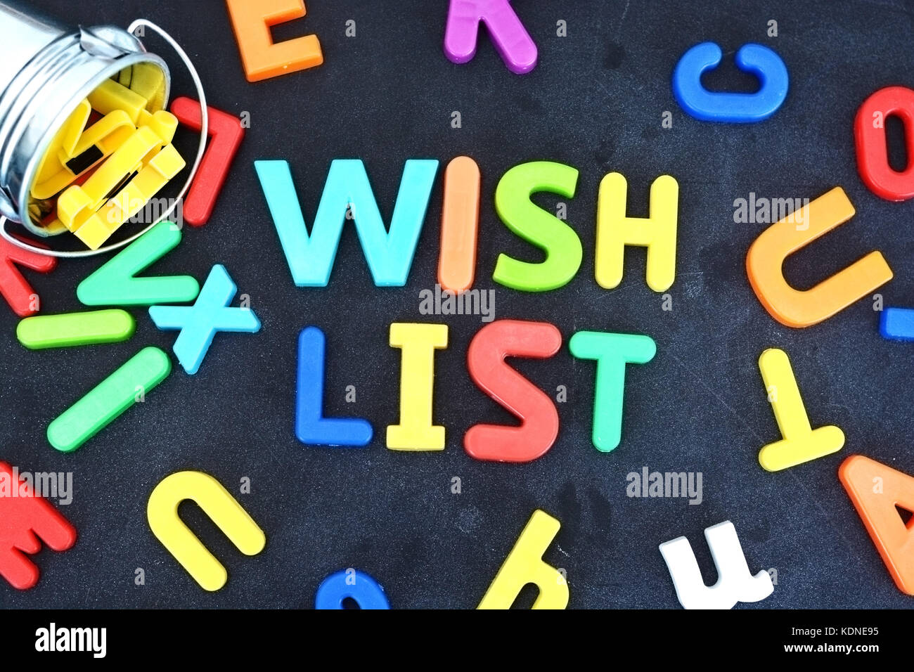 Wish list concept with colorful letters on blackboard pouring out from a metallic bucket Stock Photo
