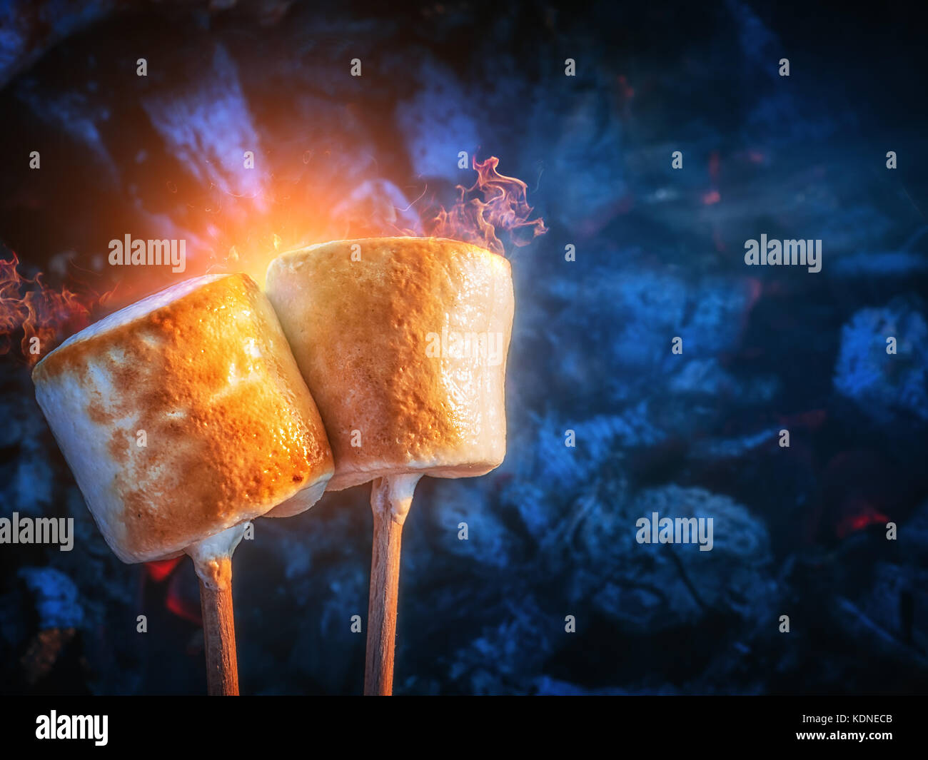 Two brown sweet marshmallows roasting over fire flames. Marshmallow on