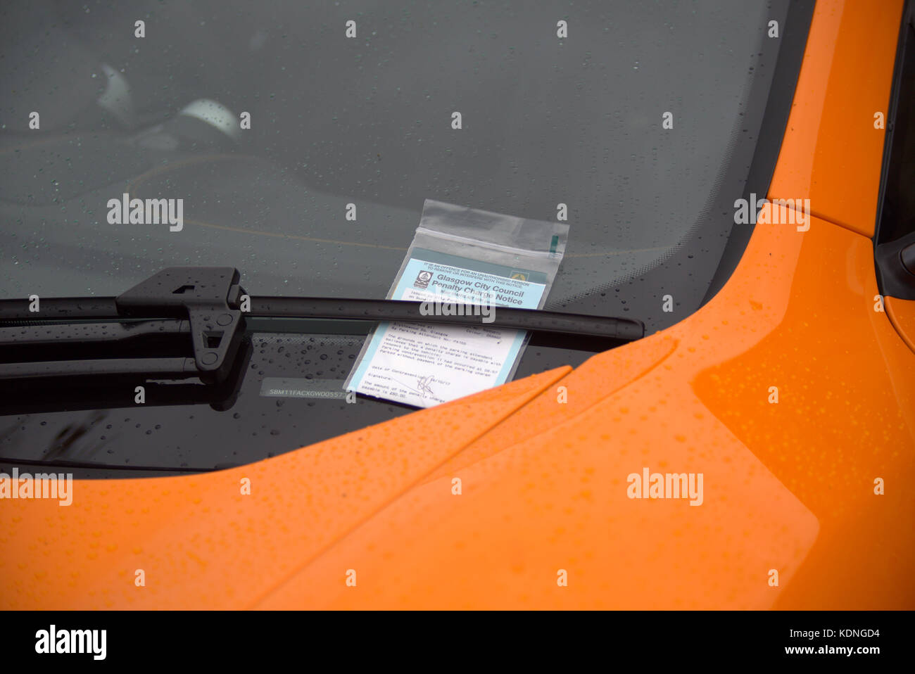close up parking ticket in the windscreen of an orange supercar sports luxury Stock Photo