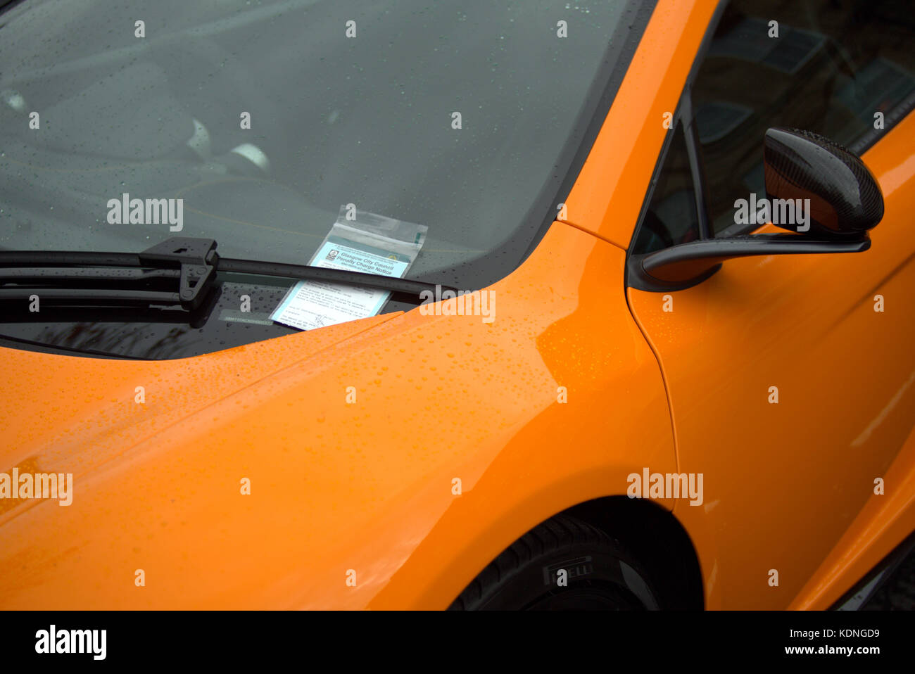 close up parking ticket in the windscreen of an orange supercar sports luxury Stock Photo