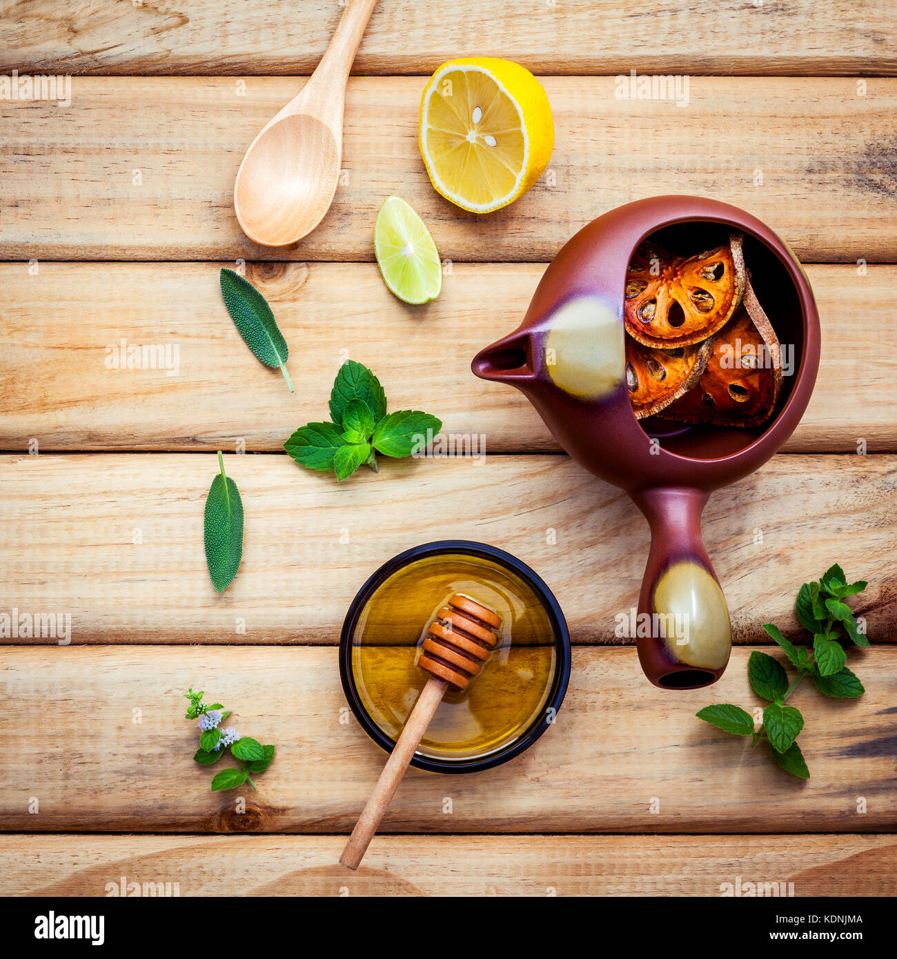 Herbal tea pot with fresh herbs sage ,peppermint ,dried indian bael, honey, lime and lemon on
