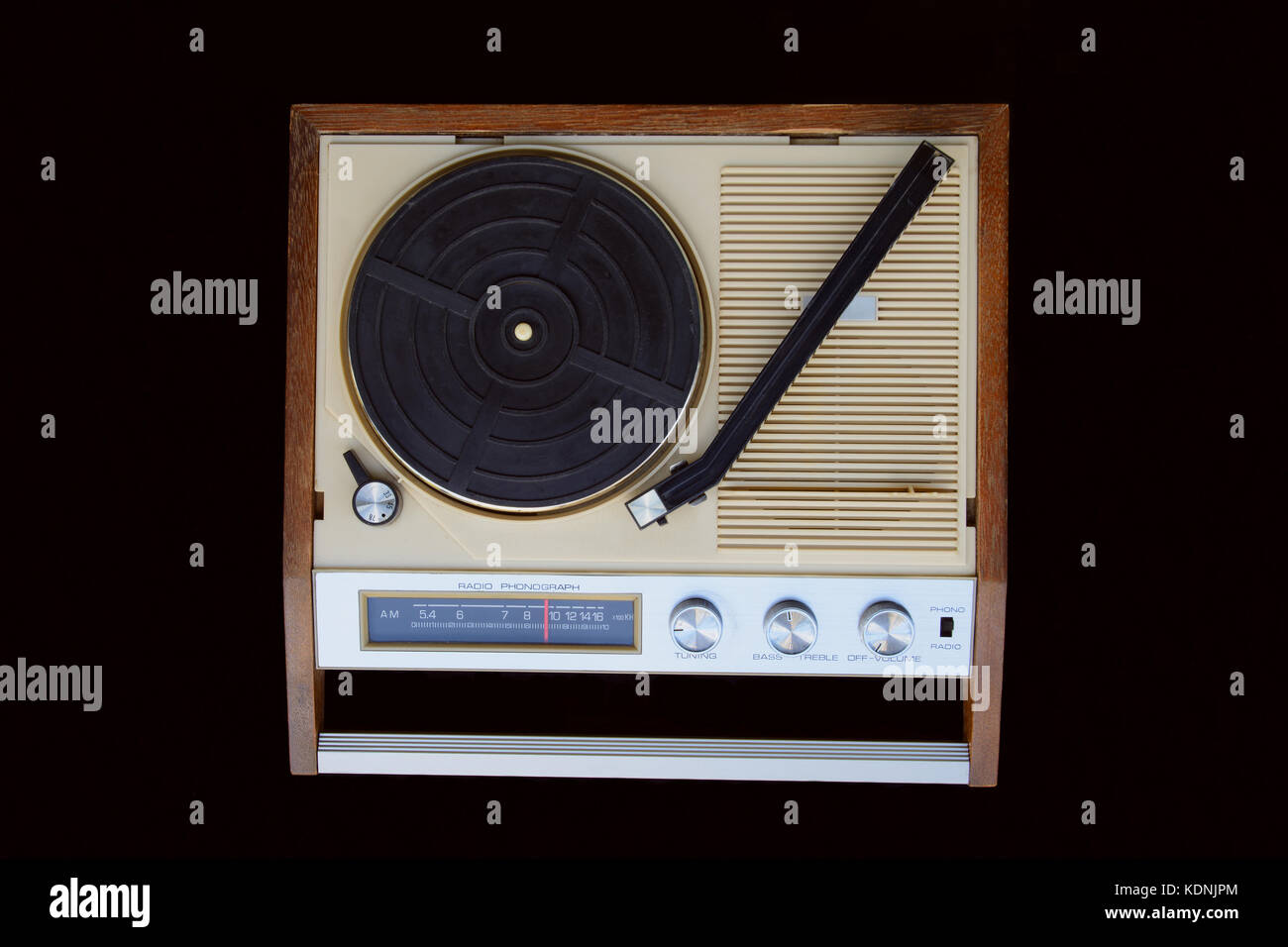 Old radio-phonograph. Turntable platter, tonearm, AM radio dial, buttons, and switches. The radio-gramophone is isolated on black background. Stock Photo