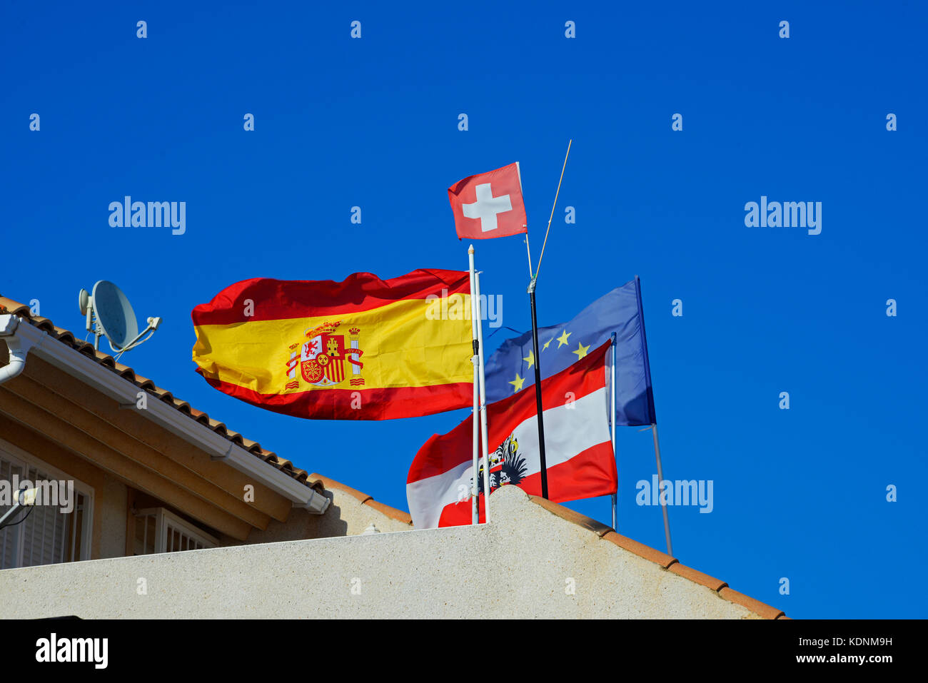 Multinational flags flying outside a property in Spain. Spanish, European, Switzerland and Austrian. European nations Stock Photo