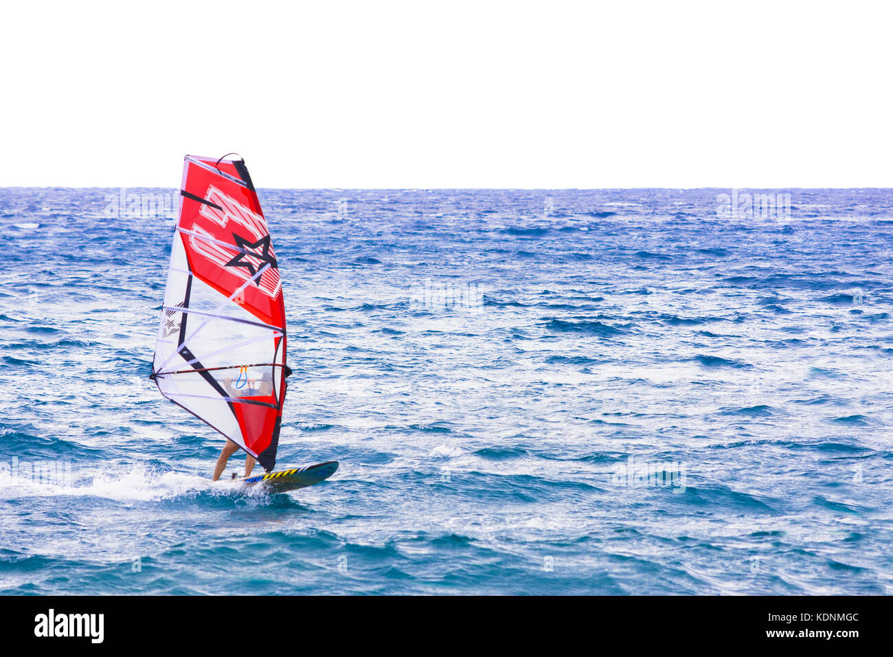 windsurfer that drives its windsurfing speed through the sparkling waves of the Ligurian Sea, in Mediterranean Sea Stock Photo