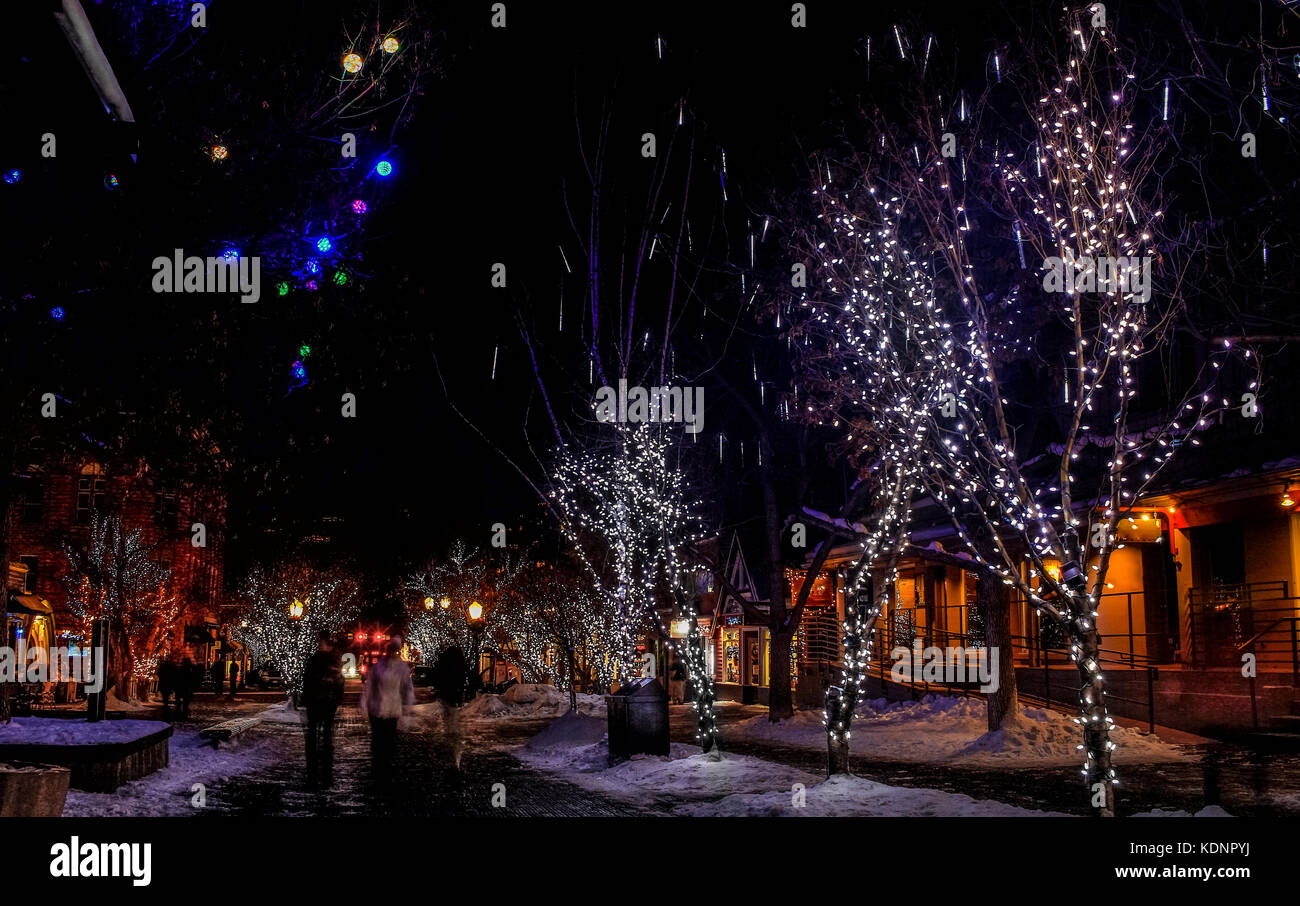 Night street in downtown Aspen, Colorado, decorated with Christmas lights and decorations; blurry figures of people walking along the street; USA Stock Photo