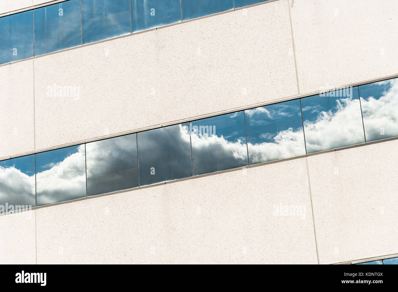 Clouds reflected in windows of modern office building Stock Photo