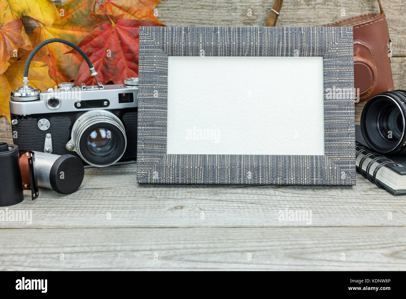 grunge wooden background with classic camera, empty photo frame, lens and film rolls Stock Photo