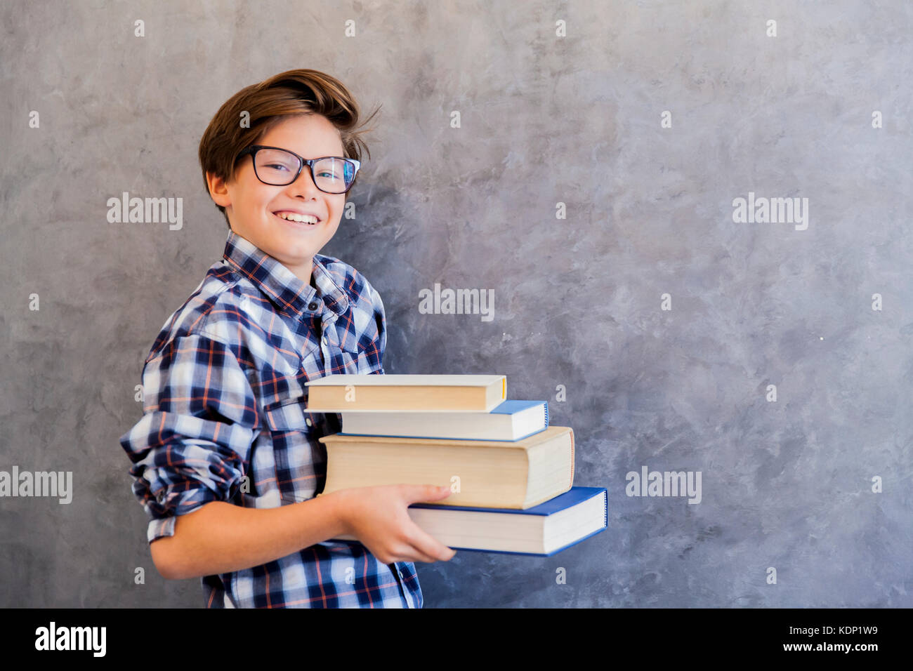 Cute teenage school boy holding books against wall Stock Photo - Alamy