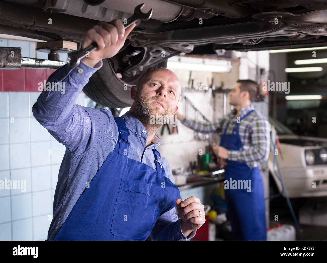 Two professional serious car mechanics repairing car at garage Stock Photo Alamy