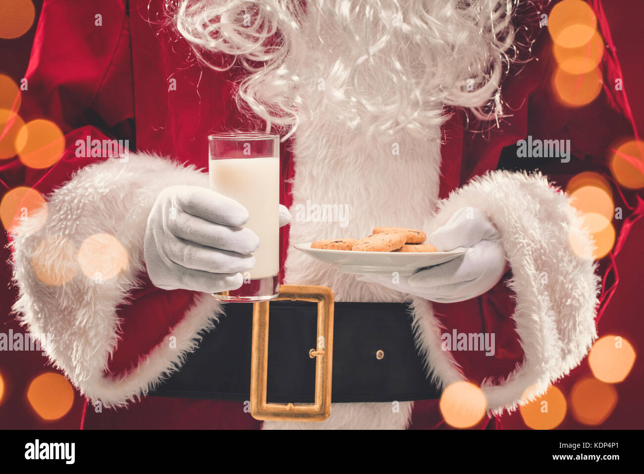 Santa Claus holding plate with cookies and glass of milk Stock Photo