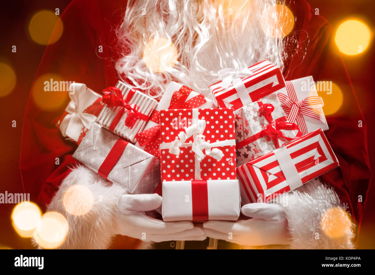 Santa Claus holding gift boxes with Christmas lights. Stock Photo