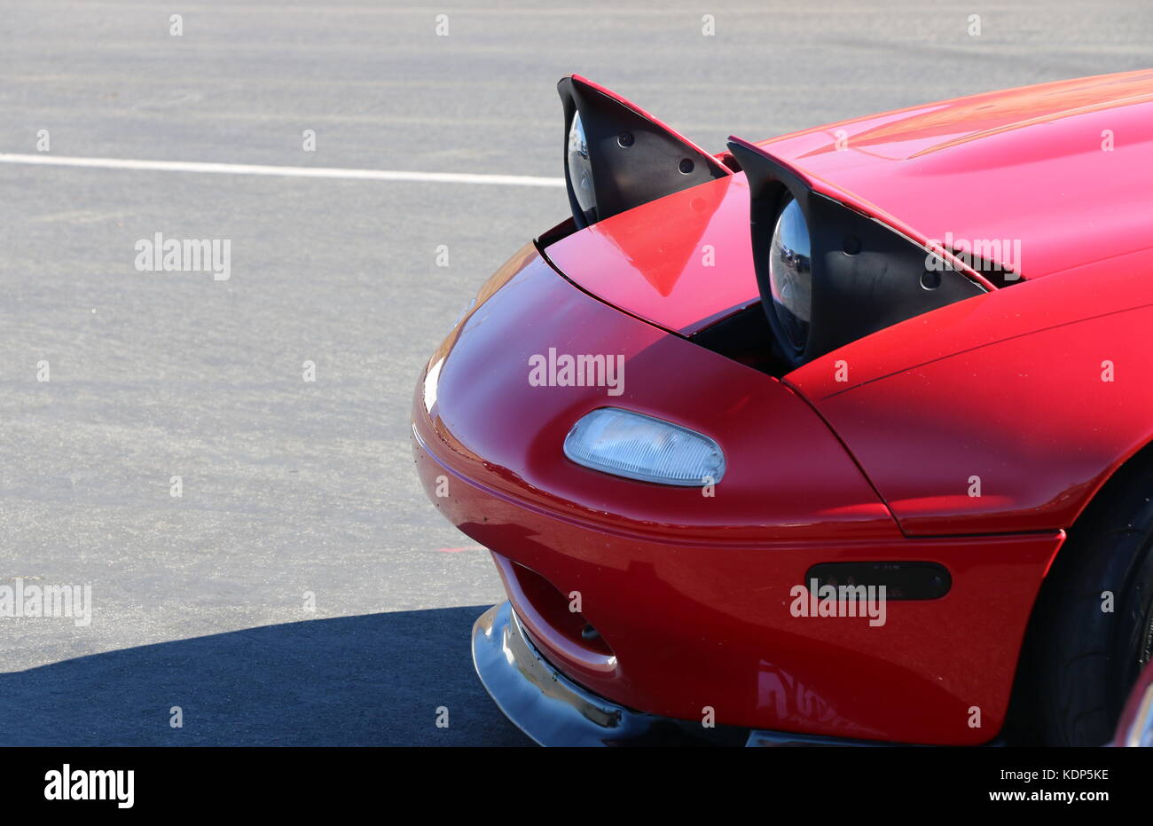 Pop up headlights on a red Mazda Miata. Stock Photo