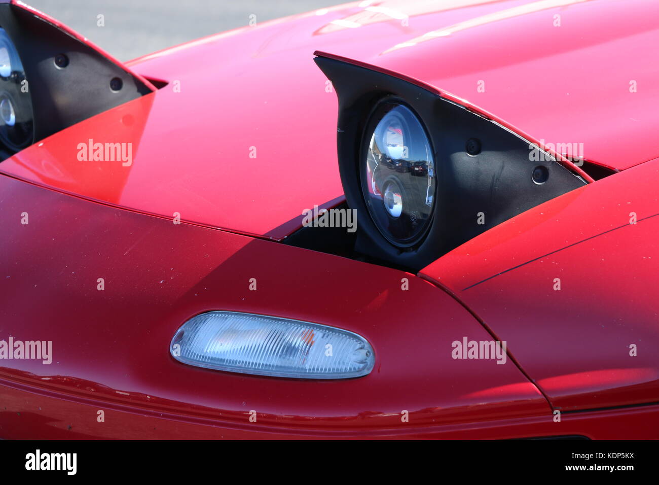 Pop up headlights on a red Mazda Miata. Stock Photo