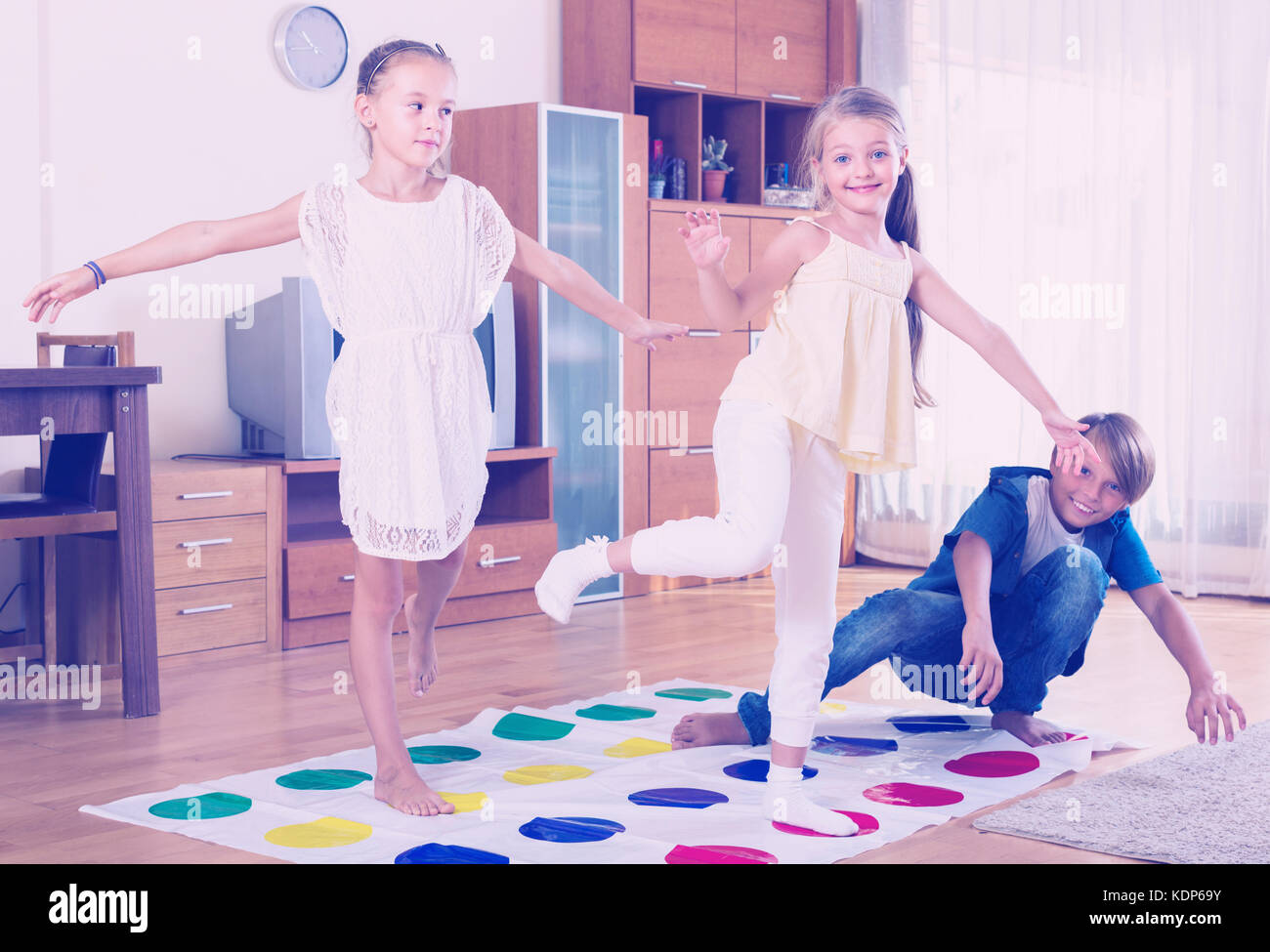 Two cute little girls and teenage boy playing twister at home Stock Photo