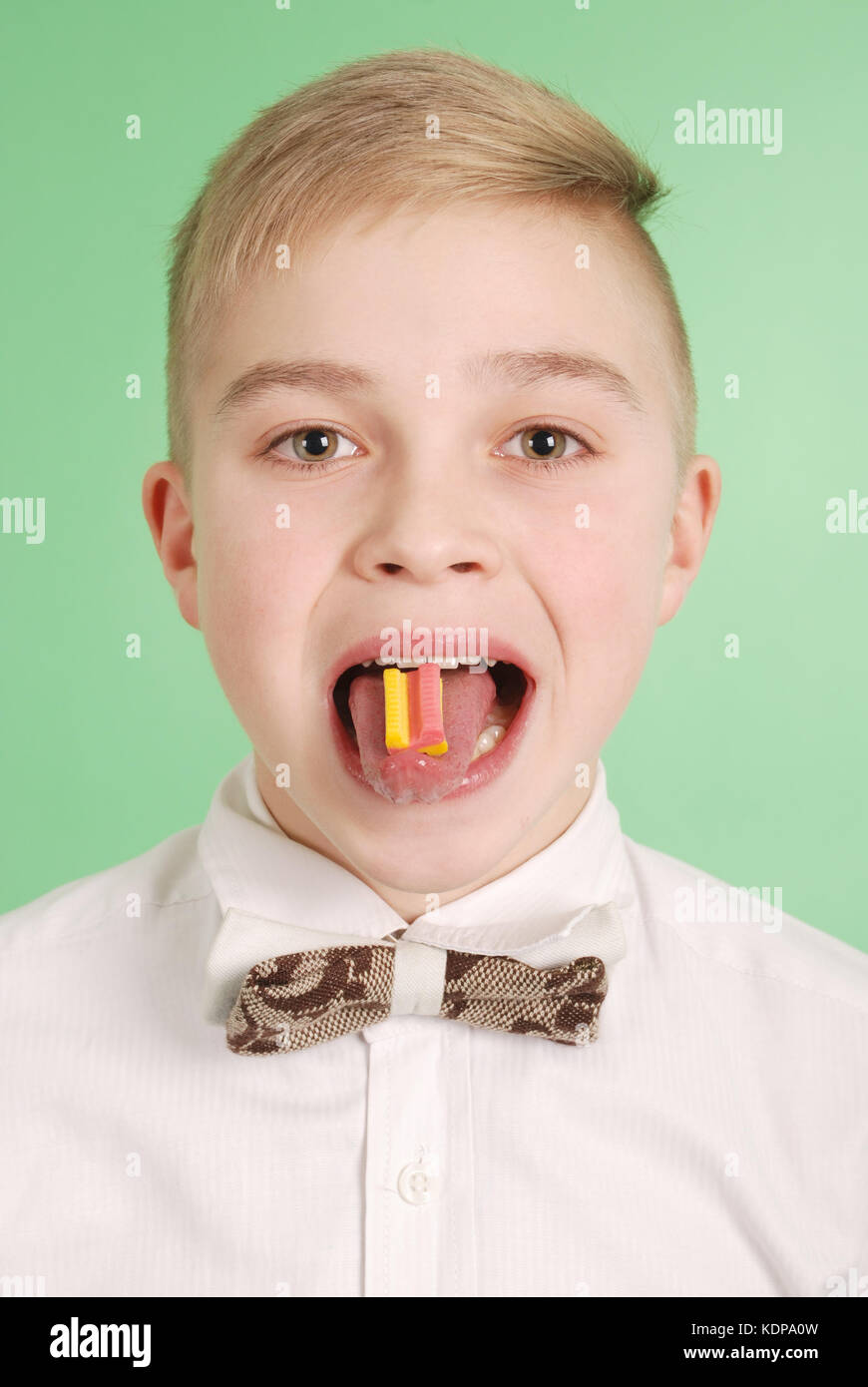 Young boy put the chewing gum on his tongue isolated on green background Stock Photo