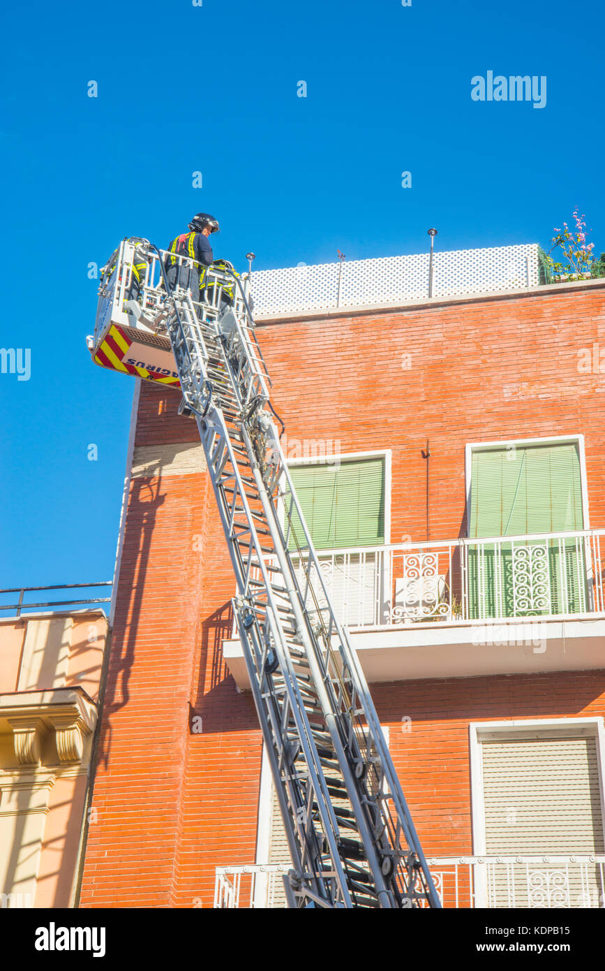 Fireman on top of the extension ladder, working on top of a house. Stock Photo