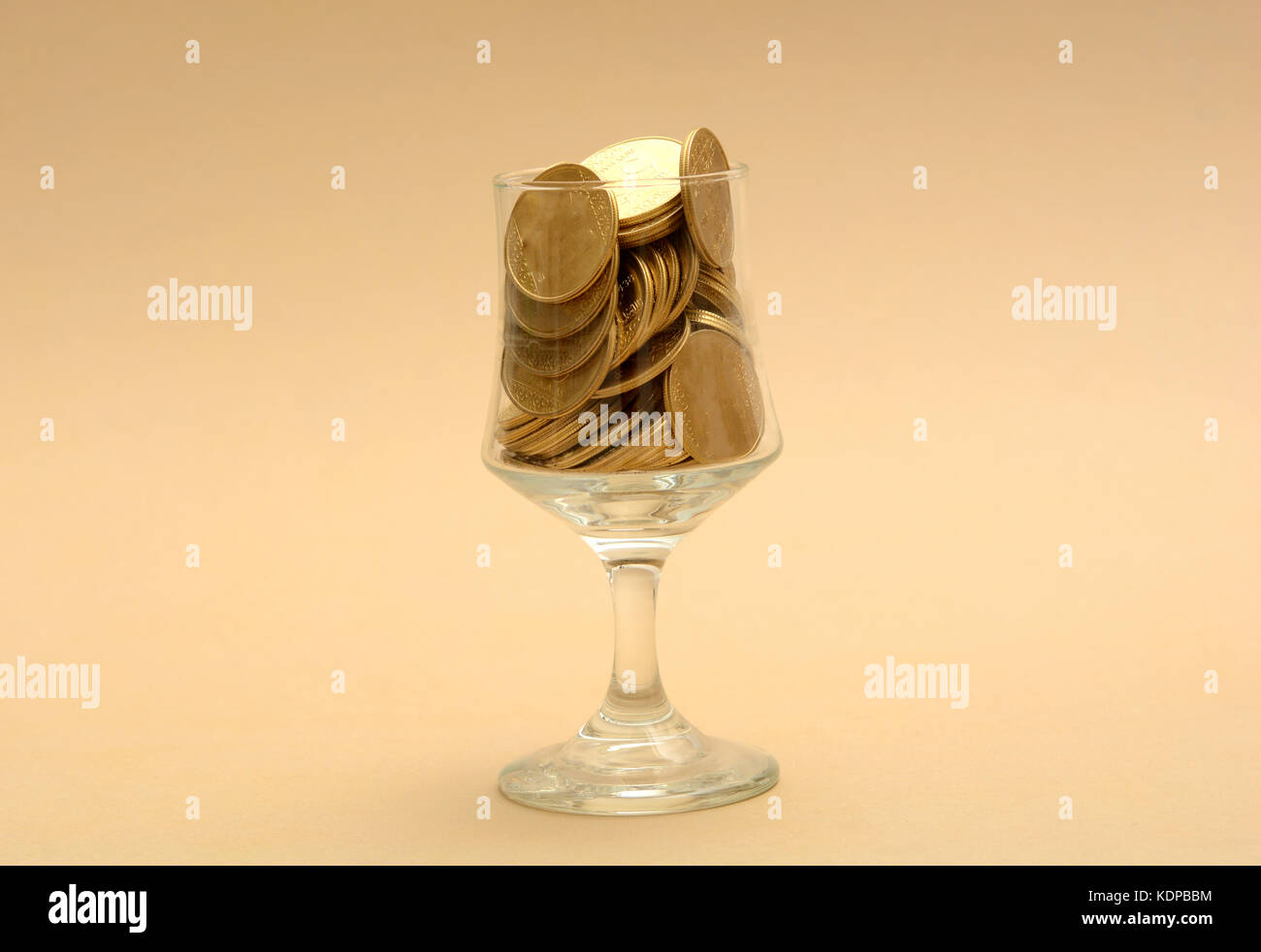 Glass full of Gold Coins - Pouring Money concept. Stock Photo