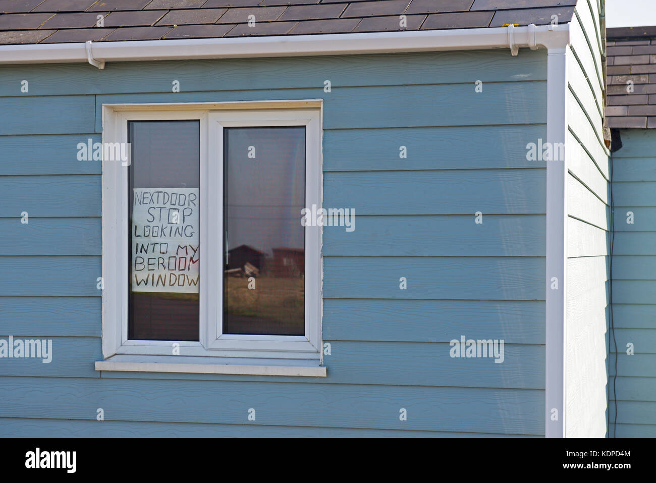 Sign on window of wooden chalet, warning neighbour not to look into bedroom window, Dungeness, Kent, England UK Stock Photo