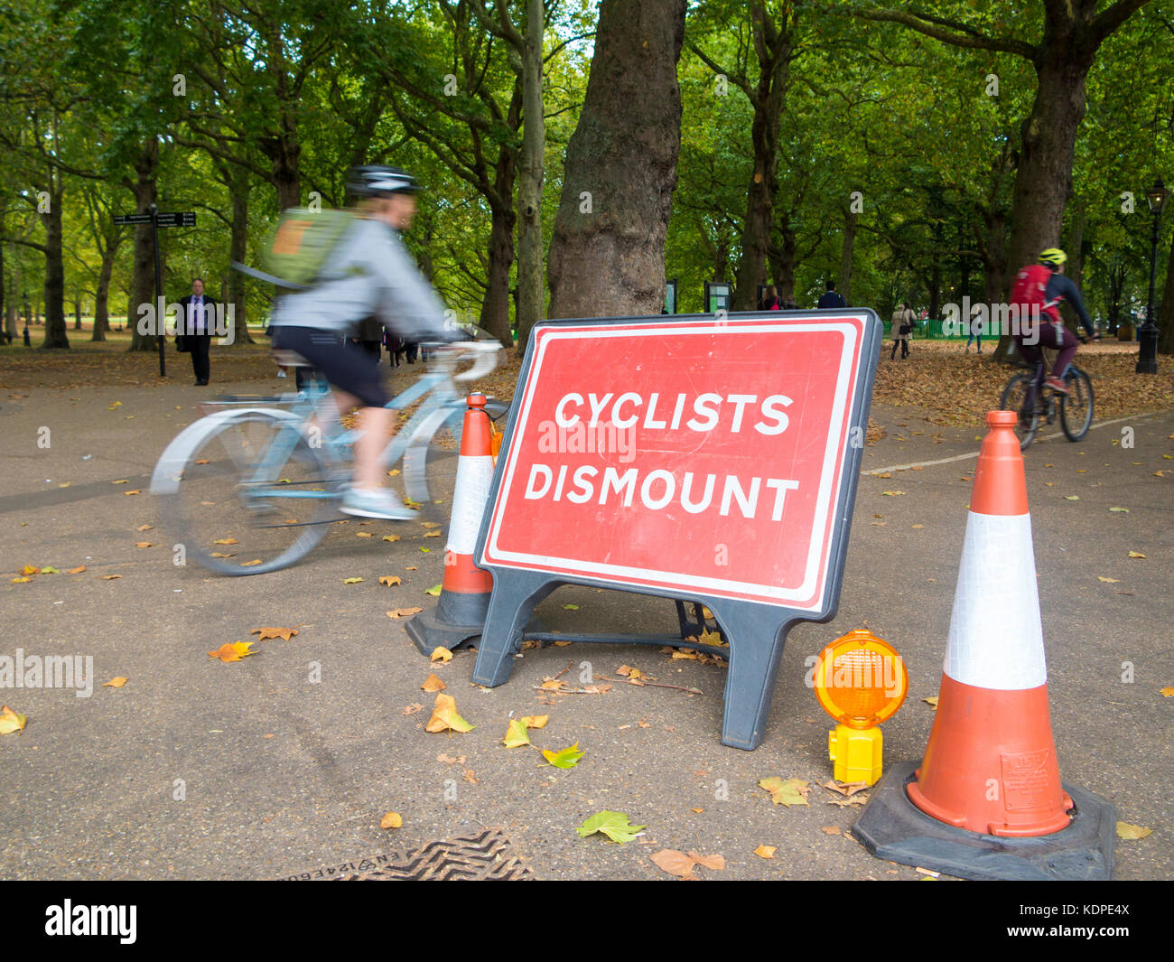 Cyclists ignore the sign that instructs them to dismount from their bicycles Stock Photo