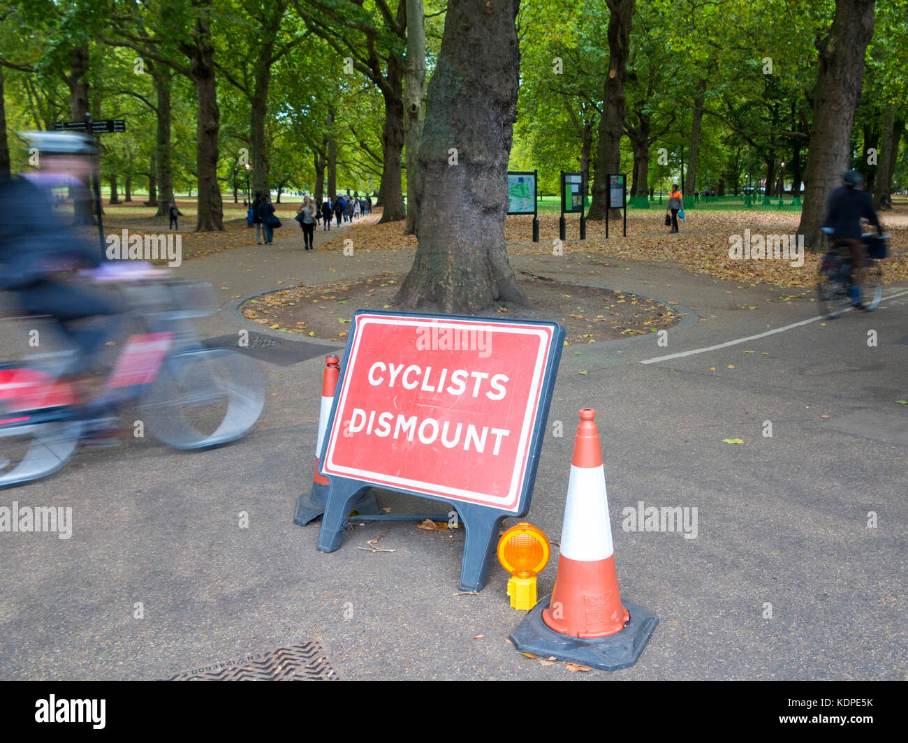 Cyclists ignore the sign that instructs them to dismount from their bicycles Stock Photo