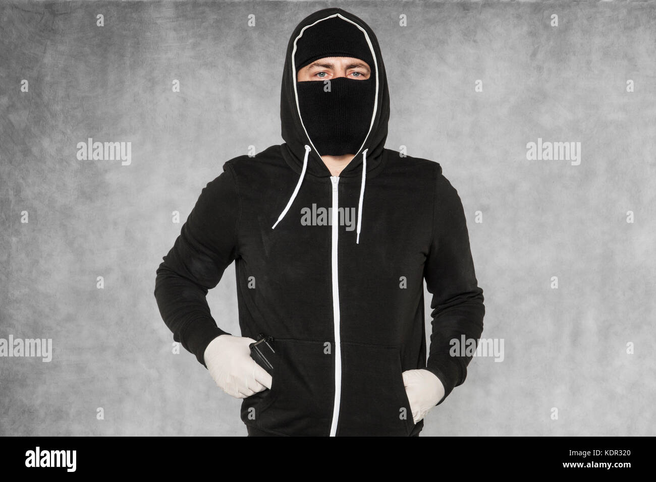 The burglar holds the gun in his pocket Stock Photo