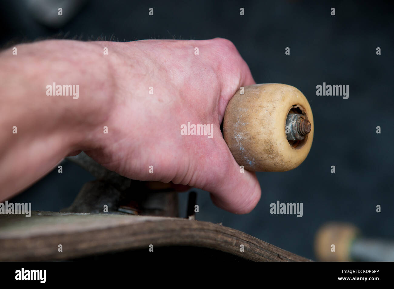 Mans hand holding a skateboard by the wheel, close up Stock Photo - Alamy
