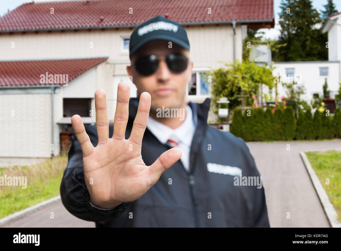 Confident Security Guard Making Stop Gesture Outside The House Stock Photo