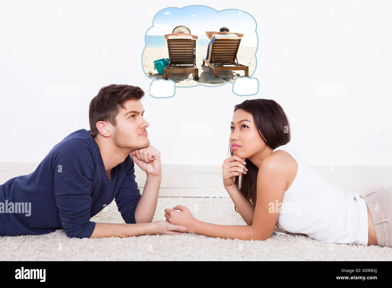 Young Couple Lying On Carpet Thinking Of Spending Vacation Together On Beach Stock Photo