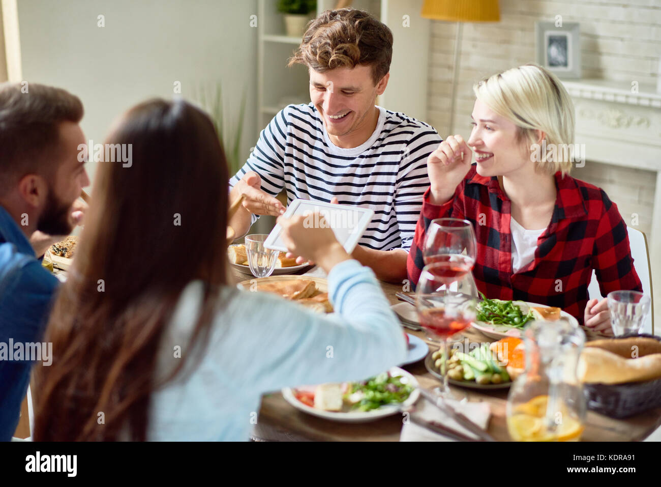 Young People Looking at Digital Tablet during Dinner Stock Photo
