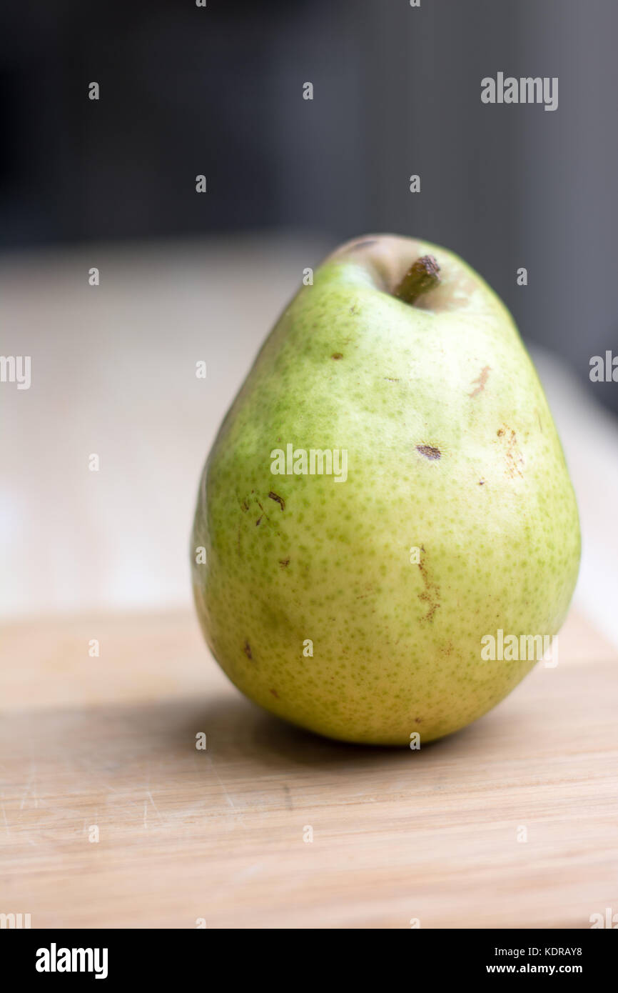 a single Bartlett green and red pear on a cutting board. Stock Photo