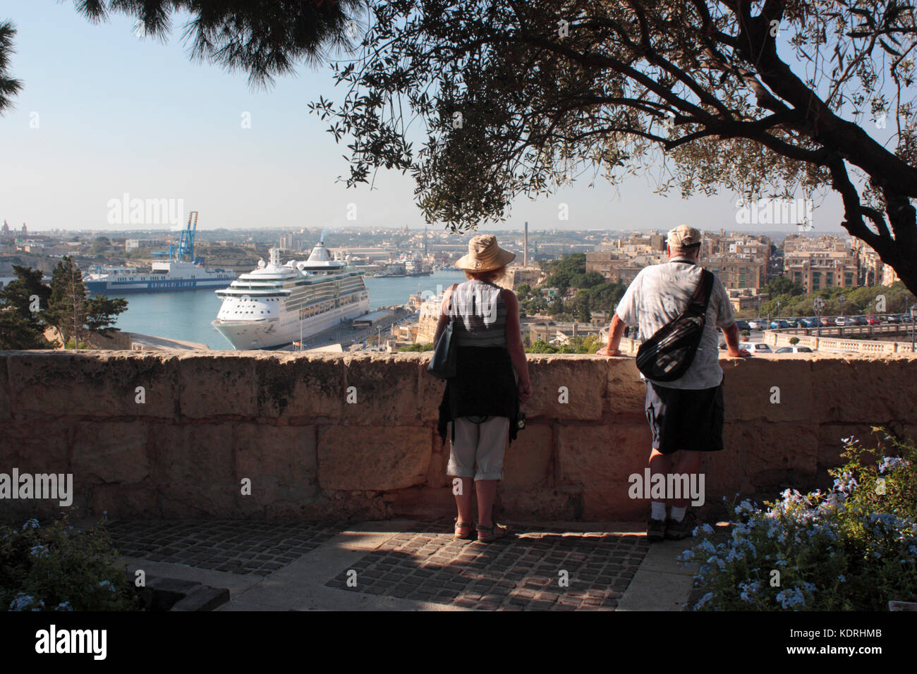 Holiday travel and tourism. Tourists taking in the view from the Upper Barrakka Gardens, Valletta, Malta, with a cruise ship visible in the distance Stock Photo