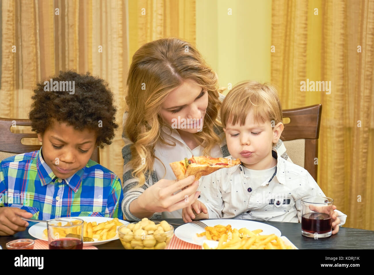 Woman feeding pizza to child. Stock Photo