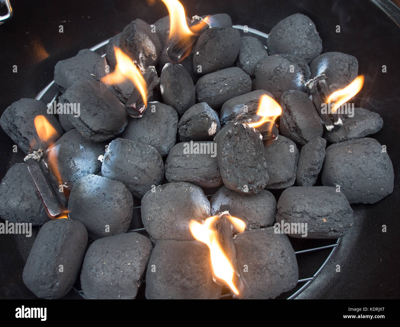 Charcoal briquettes in a barbeque being set alight by firelighters Stock Photo